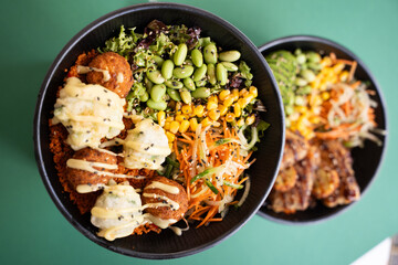 Vegetarian poke bowl with falafel, corn, edamame, and greens, top view, isolated on green...
