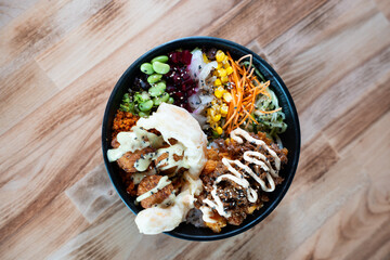poke bowl with vegetables, rice, and sauces, top view, isolated on wooden table.