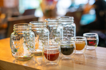 Empty mason jars and small glass cups with juice and coffee, front view, isolated on wooden table background.