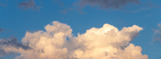 A cluster of large, sunlit clouds against a blue sky, suggesting impending twilight or dawn