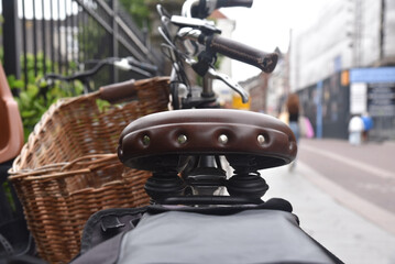 A closeup shot with shallow focus of a leather bicycle saddle on a busy shopping streed with blurred background. Concept of cycling as transport. 