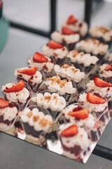 Beautiful cakes and cookies. Wedding candy bar. Delicious creamy desserts with fruits, macarons, cakes and cookies on table at wedding reception in restaurant. Luxury catering service.