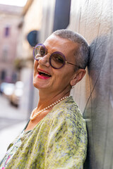 portrait of elegant mature woman smiling looking at camera leaning back against black wall