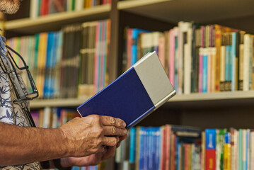 Mature man carefully reviewing a book from his home library, close-up shot with copy space