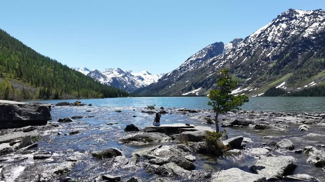 Travel to a mountain lake. A female traveler on the shore of Lake Multinskoye during a trip to the Altai Mountains. Backpacking, hiking.