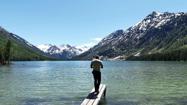 Cinematic views of a mountain lake with high mountains. Multinsky lakes are high-mountain lakes in the Altai Mountains. A man takes a selfie during a trip to the Altai Mountains.