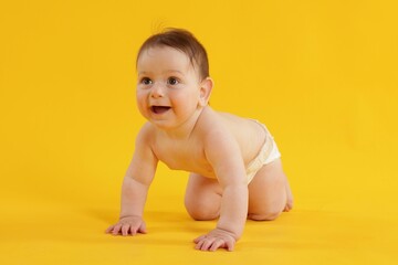 Cute little baby crawling on yellow background