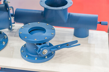 Close-up view of a flanged blue pipe fitting on a reflective surface, possibly in an industrial setting Artificial lighting, muted color palette blues, no text or humans, product photograph style