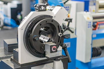 Industrial machine in a workshop setting, featuring metal components and multiple mechanical parts including gears, shafts, possibly hydraulic or pneumatic connections The image is captured from an