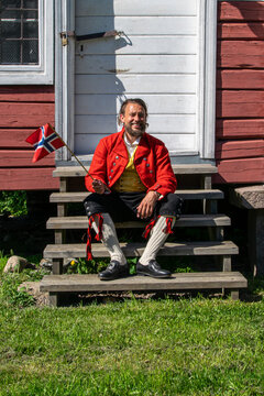 Norwegian Man in Vestfold Bunad Celebrating 17th of May in Front of Traditional Storehouse