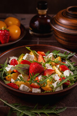 Fresh salad with strawberries, yellow tomatoes, feta cheese and arugula