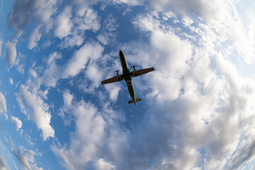 A vibrant green airplane soars gracefully against a backdrop of a bright blue sky dotted with fluffy white clouds. The image captures the beauty and freedom of flight in a serene, picturesque setting.