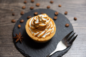 Fototapeta premium Toasted Meringue Tart on Slate with Coffee Beans. Delicious tart topped with golden toasted meringue, presented on a black slate plate with scattered coffee beans and star anise.