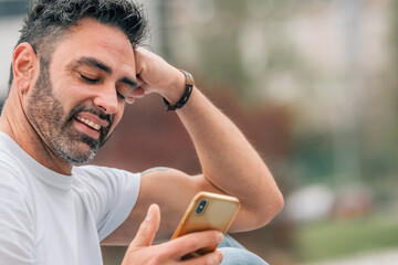 portrait of attractive man with beard outdoors looking at mobile phone