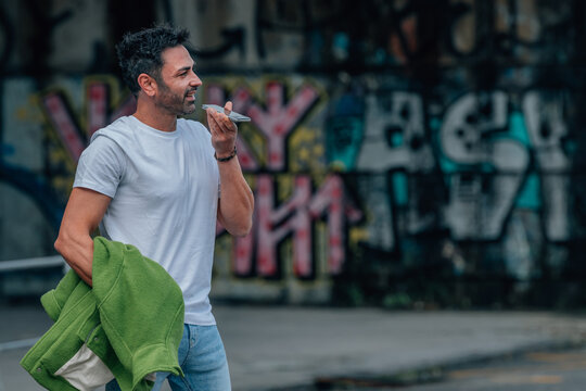 young man on the street with mobile phone sending voice message or hands free