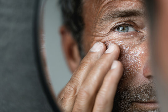 Mature man applying eye cream during skincare routine