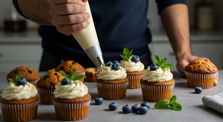 Making, decorating cupcakes, muffins with cream, blueberries and green mint leaves. Delicious homemade dessert. Pastry Process. Copy space. Pastry bag.