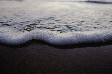 Gentle wave and bubbles on the beach after sunset