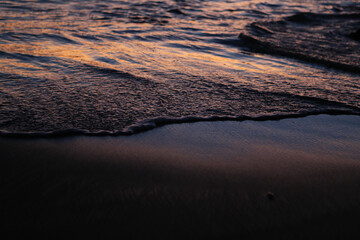 Gentle ocean waves on the beach at sunset