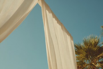 Cozy beach cabana with flowing white linen curtains beside palm trees on a clear sunny day, perfect retreat for relaxation and enjoying the ocean breeze