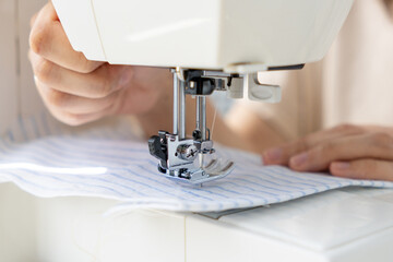 woman sews a light fabric on a sewing machine. making clothes, hobbies. a sewing studio, a clothing designer, a tailor sews on a household sewing machine.