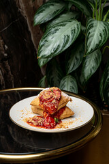 A tempting display of flaky pastries oozing with vibrant tomato sauce sits atop a stylish table. Fresh green leaves in the background enhance the appetizing ambiance