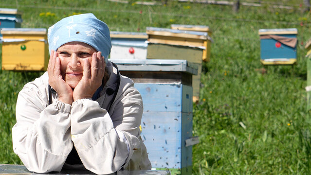Beekeeping. An elderly female beekeeper poses at her apiary. A woman in a beekeeper costume at an apiary in Altai.