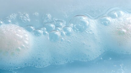 Delicate soap bubbles floating on light blue water, forming iridescent foam and revealing soft textures of cleanliness and serenity