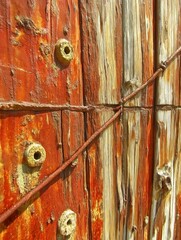 Close-up of weathered wooden surface with rusty metal bolts and wires, showcasing textures and colors, emphasizing the passage of time and natural decay in a rustic environment