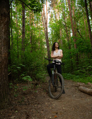 Beauty smiling woman biking on bicycle on spring trees green forest background, looking happy up....