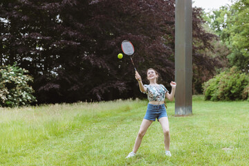 One happy girl is playing badminton in the park.
