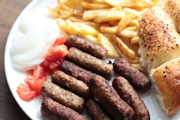 A balkan traditional meatball dish cevapi, cevapcici  on wooden table in close-up	