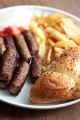 A balkan traditional meatball dish cevapi, cevapcici  on wooden table in close-up	