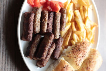 A balkan traditional meatball dish cevapi, cevapcici  on wooden table in close-up	