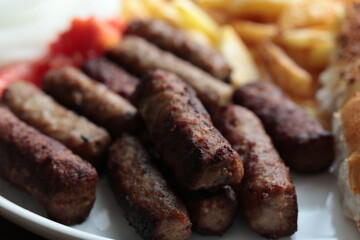 A balkan traditional meatball dish cevapi, cevapcici  on wooden table in close-up	