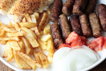 A balkan traditional meatball dish cevapi, cevapcici  on wooden table in close-up	