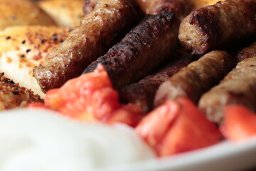 A balkan traditional meatball dish cevapi, cevapcici  on wooden table in close-up	