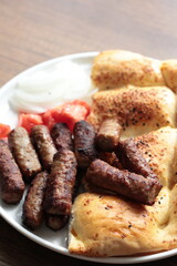 A balkan traditional meatball dish cevapi, cevapcici  on wooden table in close-up	