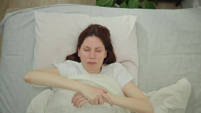 Young adult woman puts down immobile numb hand after sleep because of sleeping with a stretched arm