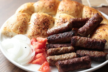 A balkan traditional meatball dish cevapi, cevapcici  on wooden table in close-up	