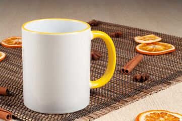Blank two-tone 11oz mug on on the table. Mug with warm spices like cinnamon, star anise, dried orange. Yellow handle. Mug mockup