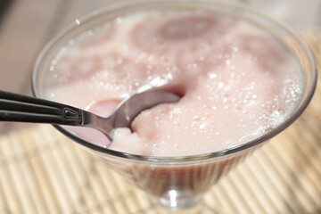 Strawberry pink pudding in glass mug on wooden table close up
