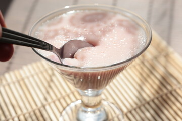 Strawberry pink pudding in glass mug on wooden table close up