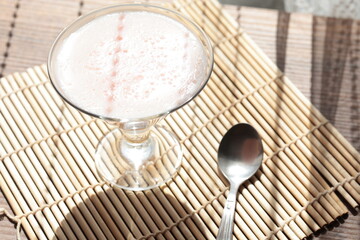 Strawberry pink pudding in glass mug on wooden table close up