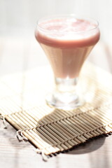Strawberry pink pudding in glass mug on wooden table close up