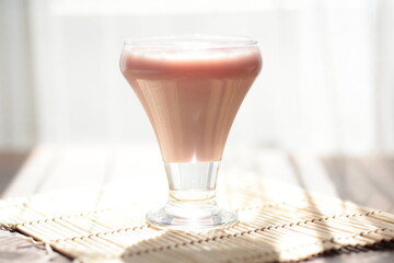 Strawberry pink pudding in glass mug on wooden table close up