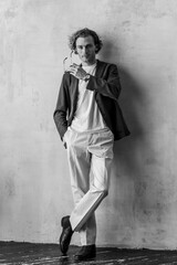 Portrait of a handsome young stylish sexy man in a white shirt, jeans posing in studio with a loft interior. Black and white. Casual clothes, modern style. Male photoshoot