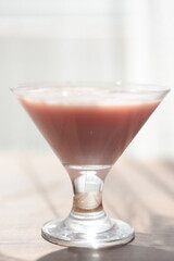Strawberry pink pudding in glass mug on wooden table close up
