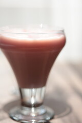 Strawberry pink pudding in glass mug on wooden table close up