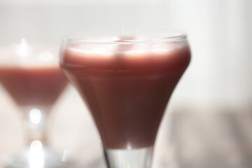 Strawberry pink pudding in glass mug on wooden table close up